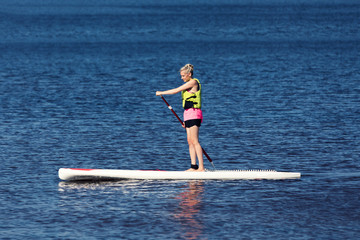 SUP fitness - woman on paddle board in the lake