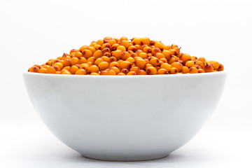 White cup full of sea-buckthorn on white background.