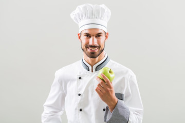 Chef is holding apple  on gray background.