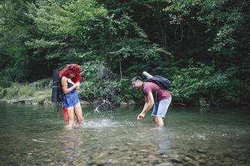 Fototapeta premium Happy young hikers couple enjoying in adventure. They camping and having fun while walking through the wild mountain river.
