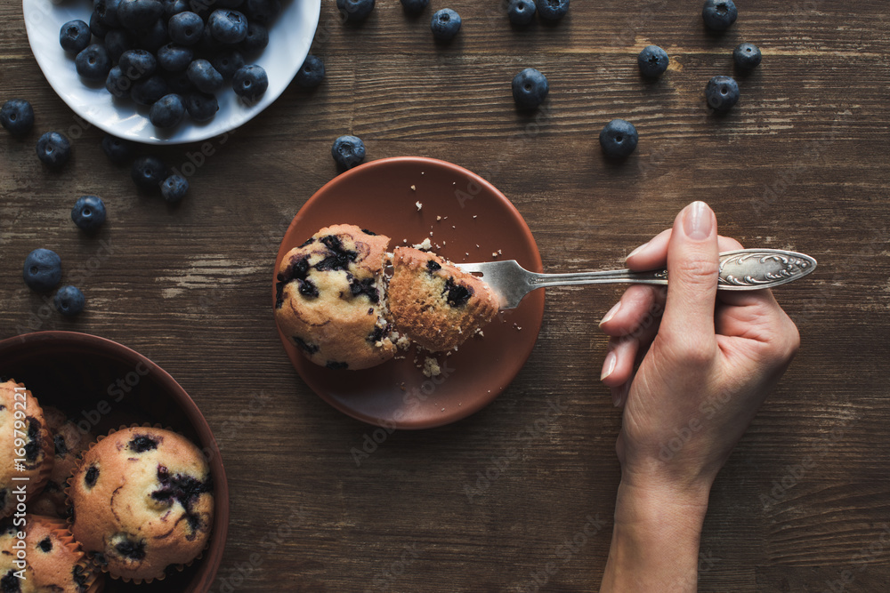 Wall mural person eating muffin with blueberries