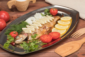 fish baked in foil on a tray with lemon greens and spices