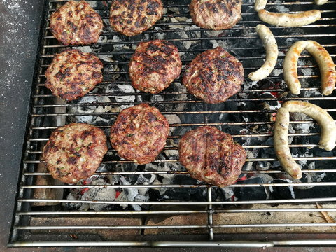 Frikadellen und Bratw&uuml;rste auf dem Holzkohlengrill bei einem Barbecue auf dem Bauernhof im Sommer im Pfaffenwinkel in Rudersau bei Rottenbuch im Kreis Weilheim-Schongau in Oberbayern