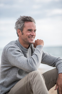 Portrait of a Gray haired man sitting on a rock at the beach