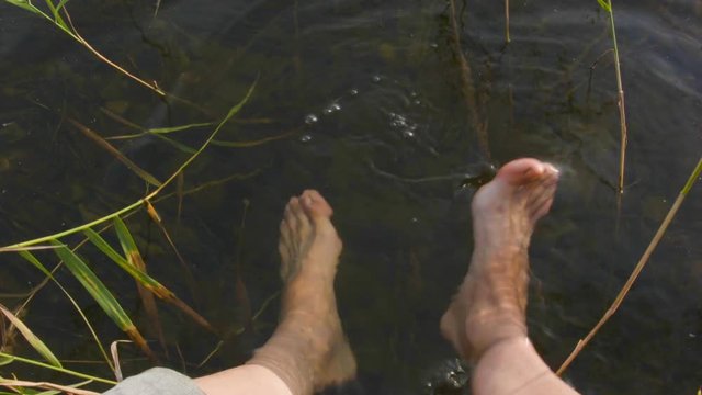 Man sitting with bare feet in the water, concept of relaxation
