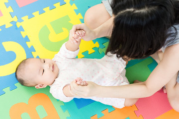 Mother playing with adorable baby on colorful eva foam indoors