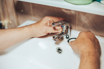 Man repair and fixing leaky new faucet in bathroom