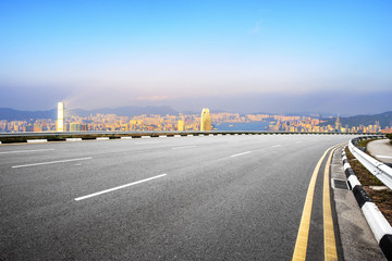 empty road with cityscape of modern city in blue sky