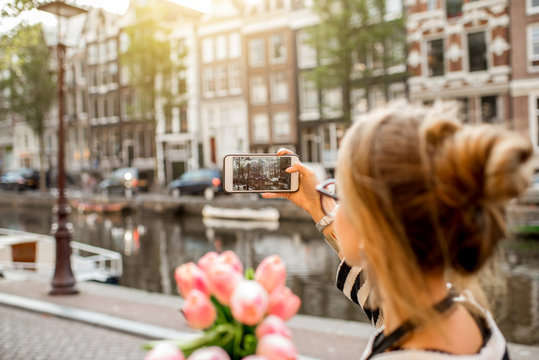 Woman photographing with phone beautiful cityscape during the morning in Amsterdam city
