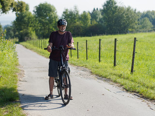 Älterer Mann macht Radtour mit E-Bike in schöner Landschaft