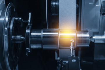 The cylindrical grinding machine with the steel shaft.Hi precision manufacturing concept.
