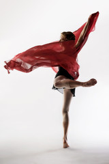 graceful ballet dancer dancing on a light background with a fluid, lightweight red cloth