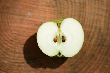 Apple cut in half, top view, on a wooden plate in the sun