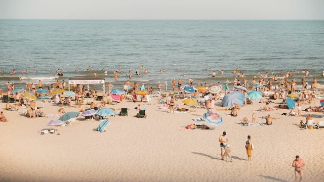 Wide view of the sandy sun beach with people on vacation having sunbath near the sealine