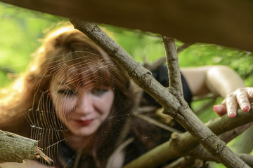 Web in the forest, in front of the defocused face of a girl, gothic style