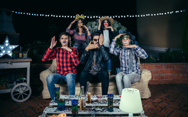 Young friends with costumes and atrezzo having a funny hands dance on a outdoors party. Friendship and celebrations concept.