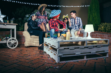 Pallets table with beverages and confetti on top in a outdoors party with people talking in the background