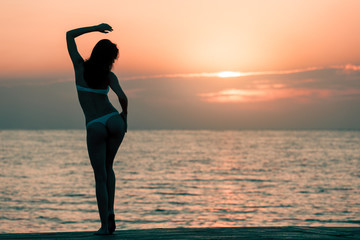 Fototapeta na wymiar Beautiful woman silhouette over ocean sunrise background