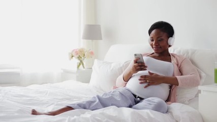 pregnant woman in headphones with smartphone - Powered by Adobe