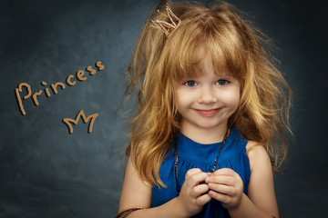 charming little girl with her hair in the blue dress and the crown Princess looks in the frame © olgamazina
