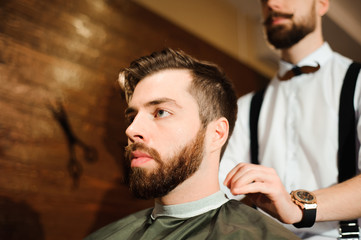 Master cuts hair and beard of men in the barbershop