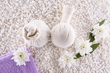 Obraz na płótnie Canvas Spa. Still life. Herbal balls, a towel and flowers on a background of white pebbles.