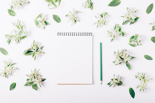 Notepad and pencil among the green flowers