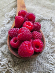 large fresh red raspberry berries, poured into a wooden spoon.