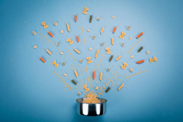 Dishes for eating with different types of spaghetti various forms near it. Food Concept. Components products. Cooking concept. Blue background top view.