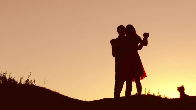 Couple in love dancing nature silhouette at sunset and kissing. Loving man and woman with dog dancing silhouette slow motion video