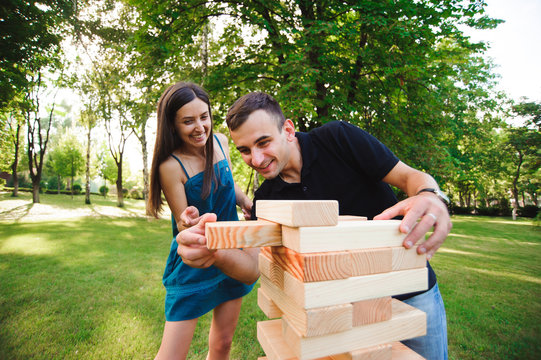 side view of men and women playing jenga game in a park