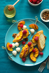 Sandwiches with ricotta cheese, mozzarella, raspberry, honey and grilled peach on turquoise background. Selective focus. Vibrant colors