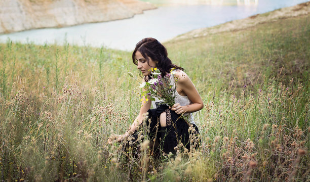 Giovane donna che raccoglie fiori selvatici in un prato di montagna