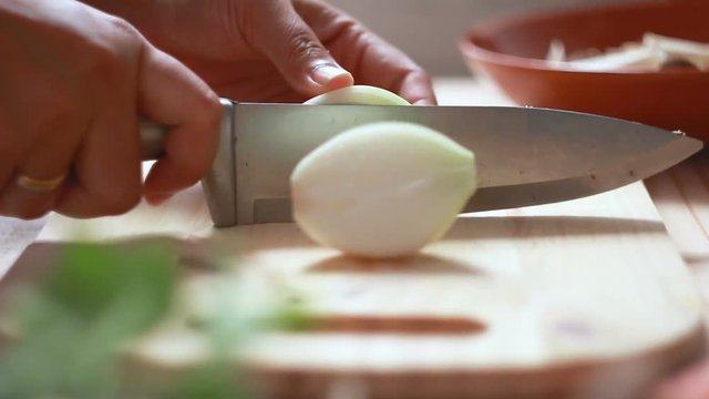 Close up shot hands of women using kitchen knife slide cut fresh onion on wooden cutting boar preparing for cooking