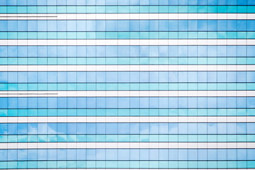 Blue sky and clouds reflecting in windows of modern office building