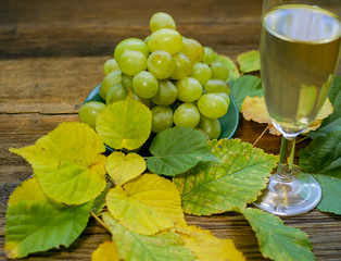 Grapes. Аutumn leaves. A wooden table.