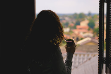 Woman watching the view from window drinking chimarrao - Rio Grande do Sul - Southern Brazil.