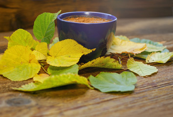 Coffee with grated chocolate. autumn leaves. Wooden table. Side.