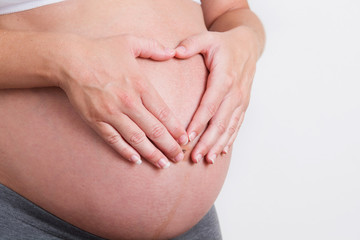 Pregnant Woman holding her hands in a heart shape

