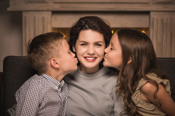 kids kissing smiling mother