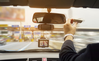 Man driving car using navigator and holding electronic toll collection system device
