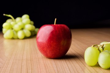A red apple and green grapes on the table