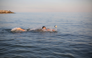 Young boy plays water polo in the sea in summer