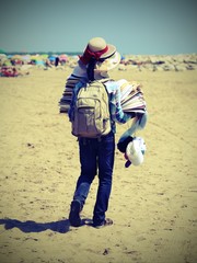 Walker with many hats and fashion accessories walks on the sandy