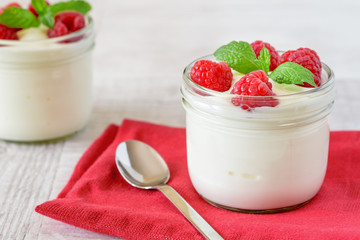 White yogurt with fresh raspberries in glass bowl.