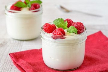 White yogurt with fresh raspberries in glass bowl.