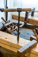 Auger stands in a wooden beam. Old carpentry workshop with obsolete tools used. Vintage woodworking hand tools of an ancient carpentry.