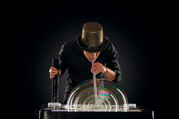 Man artist blowing many soap bubble. Soap bubble show in black studio.