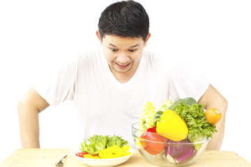 Asian man showing dislike expression of fresh colorful vegetables isolated over white background