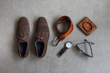 Men's casual outfits with leather shoes and accessories on gray background, travel items